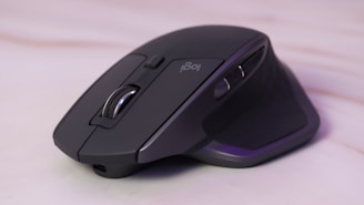 A wireless ergonomic mouse resting on a textured mouse pad beside a notebook.
