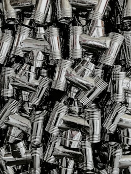 Close-up of polished stainless steel flanges and pipes stacked in a factory