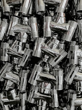 A dense collection of shiny, metallic pipe fittings with threaded sections. The fittings have reflective surfaces and are stacked in an organized, overlapping fashion.