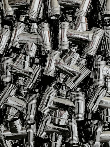 A dense collection of shiny, metallic pipe fittings with threaded sections. The fittings have reflective surfaces and are stacked in an organized, overlapping fashion.
