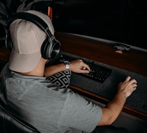 a man wearing headphones and sitting at a desk with a computer