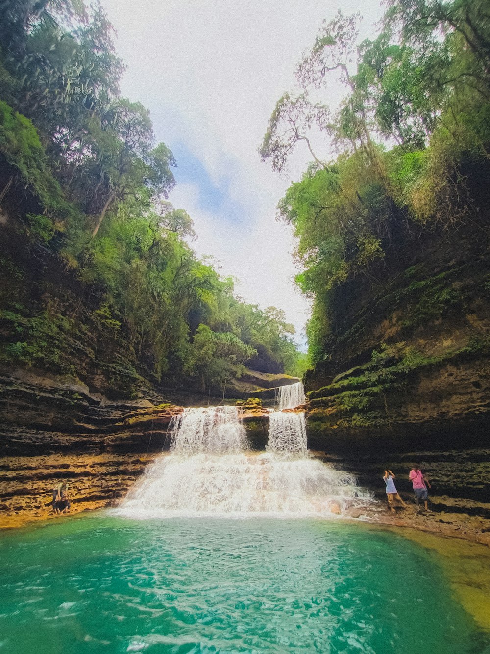 people standing near a waterfall