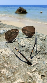 Unisex sunglasses with polarized lenses placed on a rock near the ocean