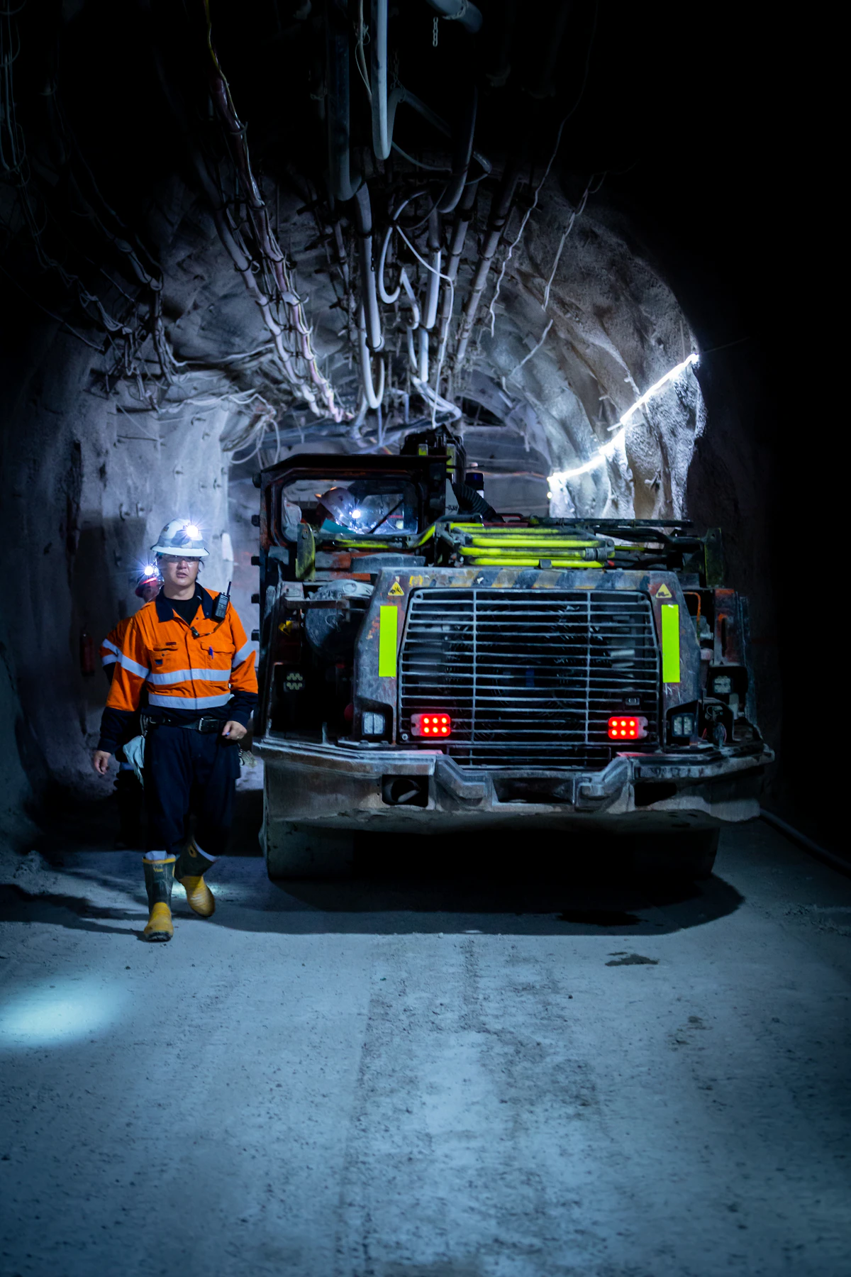 Equipo de minería subterránea junto a un trabajador con indumentaria de seguridad