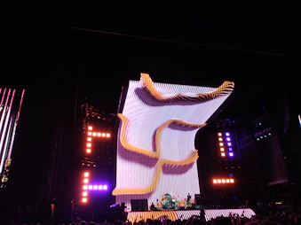 A dynamic concert stage illuminated with electric blue and magenta moving head lights cutting through haze.