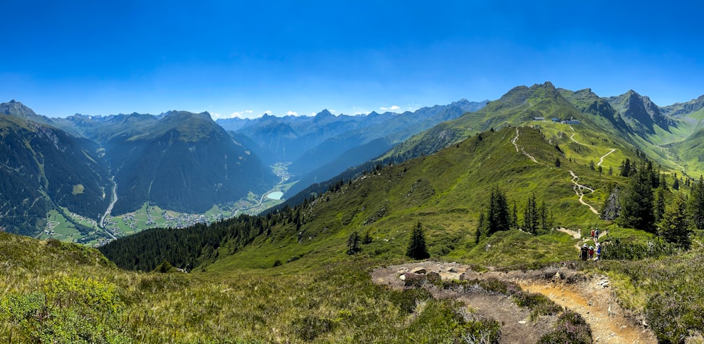 a group of people walking on a trail in a valley between mountains