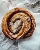 Close-up of a cinnamon swirl bun with golden crust and sugar glaze.