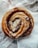 Close-up of a warm cinnamon roll with icing dripping over the edges on a rustic wooden table.