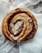 Close-up of a warm cinnamon roll with icing dripping over the edges on a rustic wooden table.
