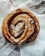 Close-up of a warm cinnamon roll with glistening sugar glaze on a rustic wooden table.