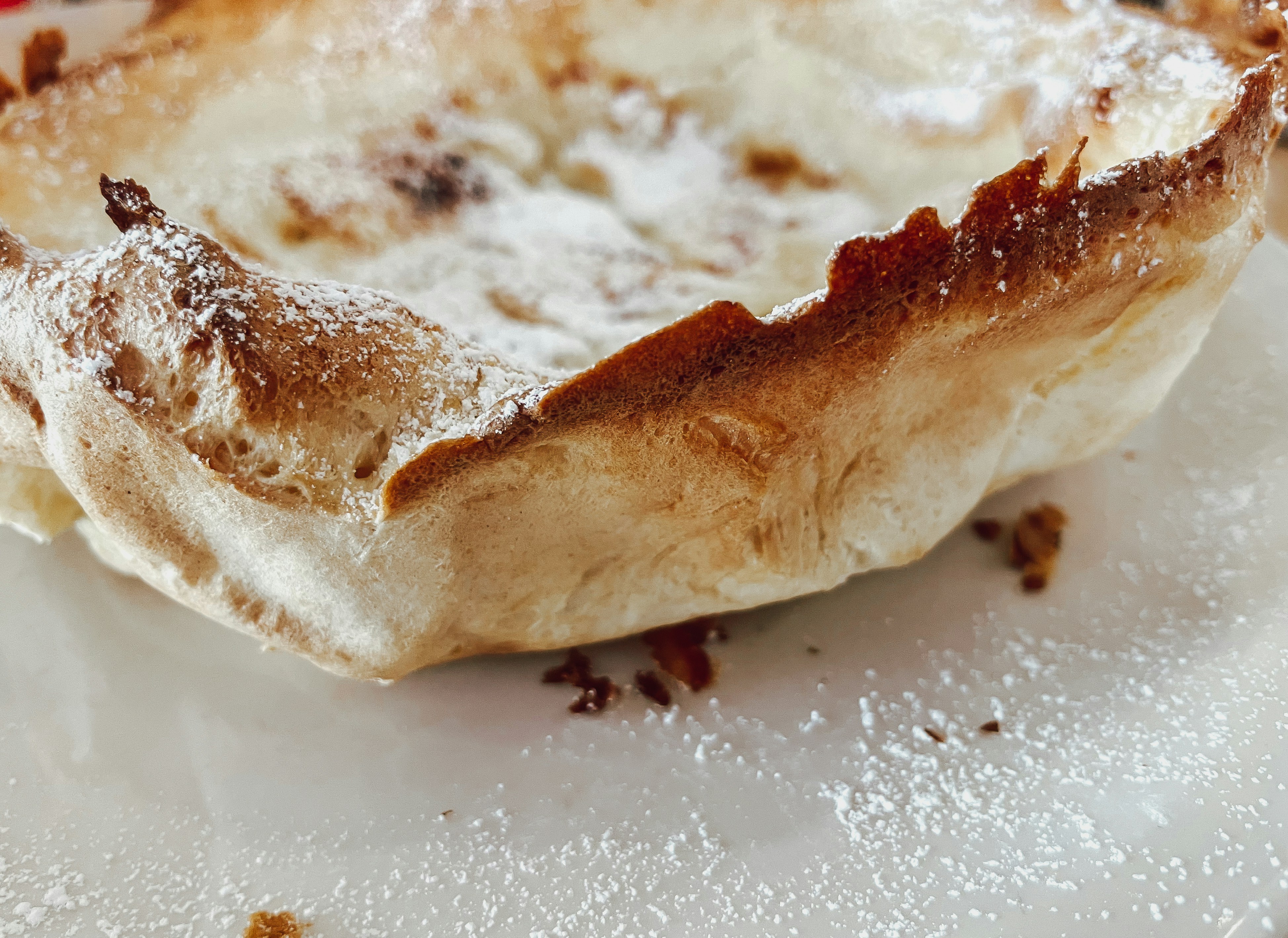 Close-up of golden pastries arranged on a wooden board with scattered powdered sugar in warm café light