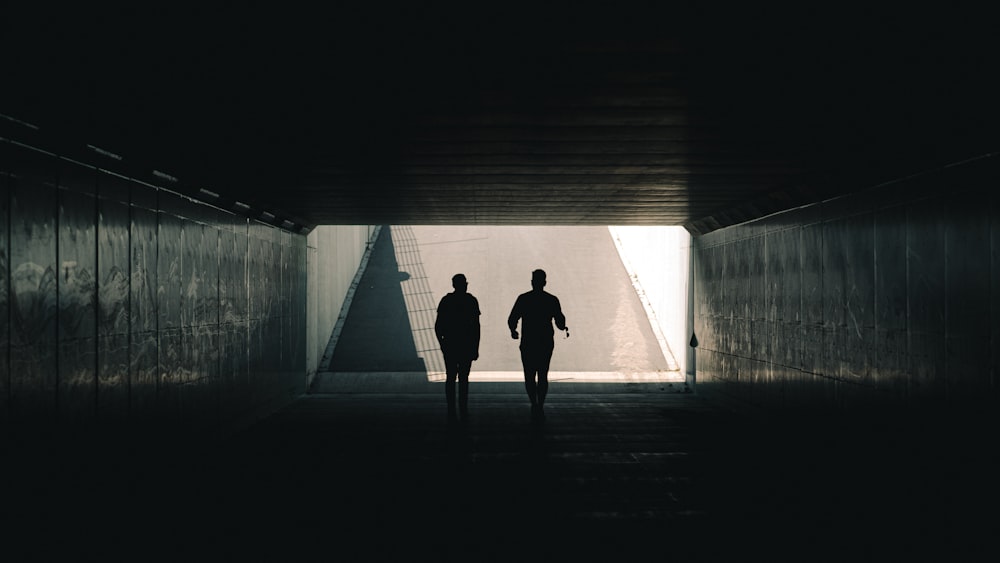 a couple of people walking down a dark hallway