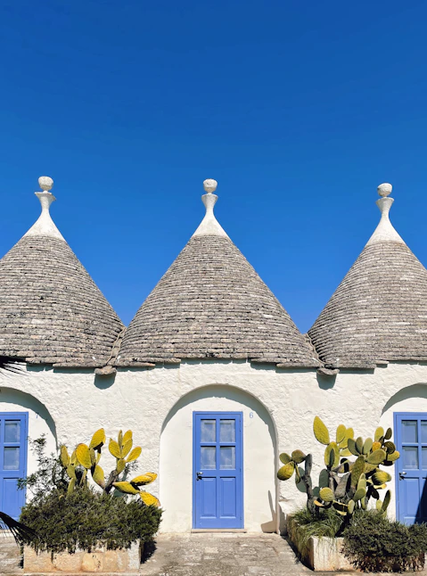 a house with blue doors and a roof with a blue door with Alberobello in the background