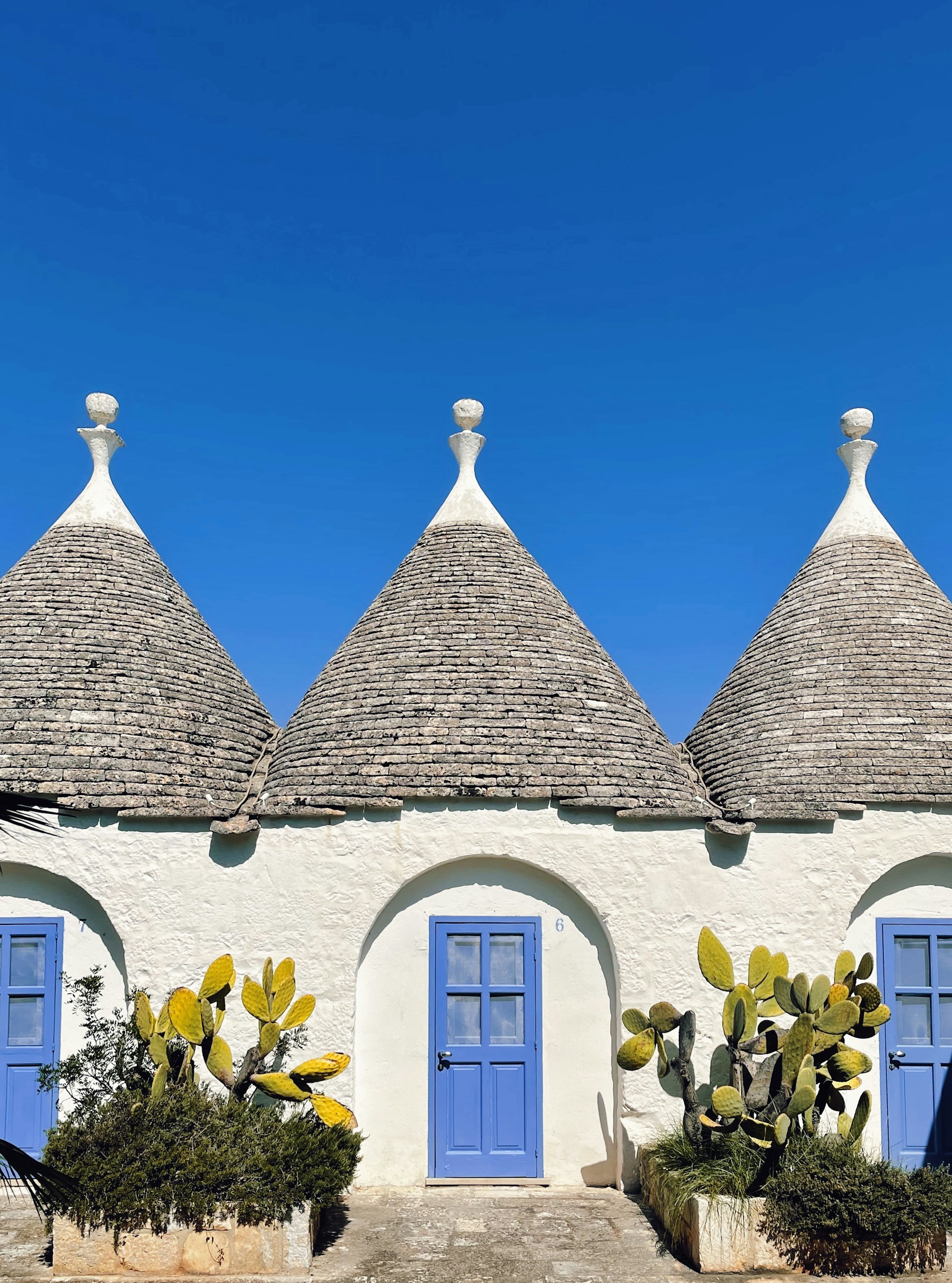 a house with blue doors and a roof with a blue door with Alberobello in the background
