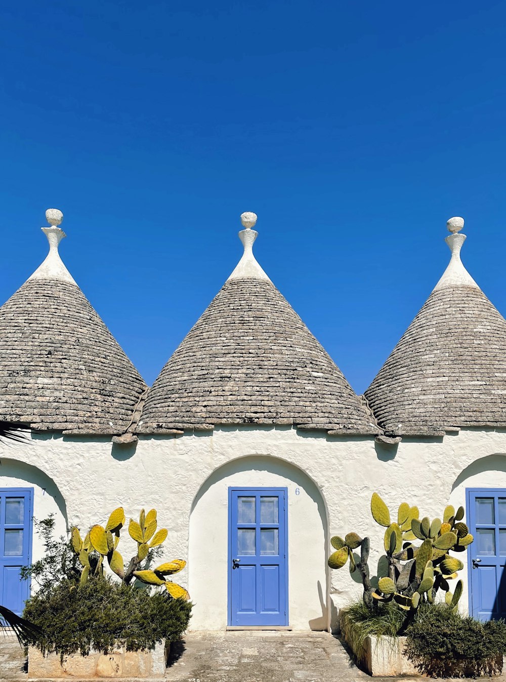 a house with blue doors and a roof with a blue door with Alberobello in the background