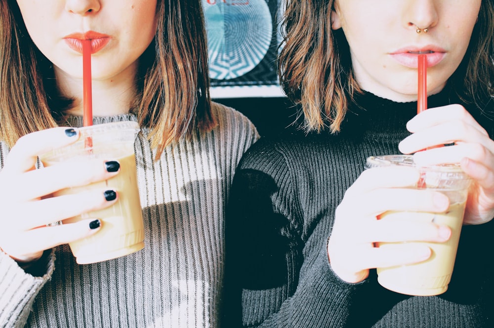 Two friends sipping cold drinks with red straws