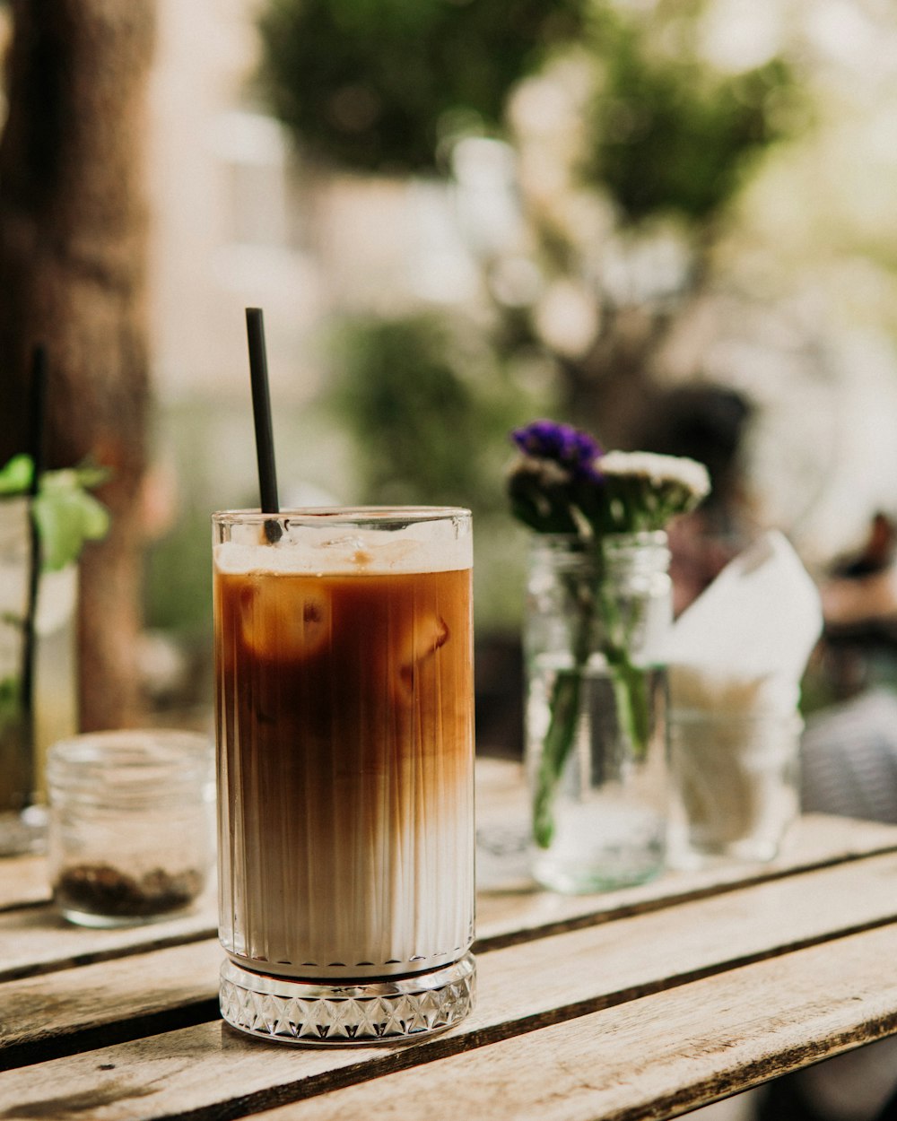 a glass of brown liquid with a straw on a wooden table