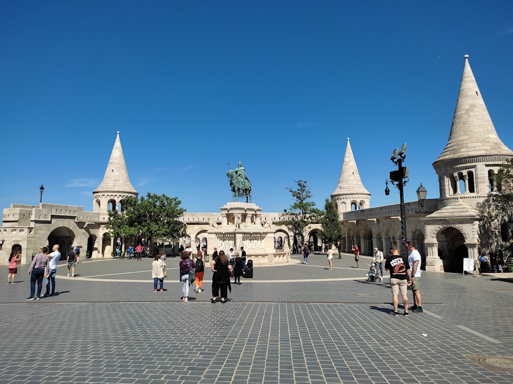 a group of people walking around a courtyard with a statue in the middle