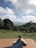 A person stretching their legs in a park, looking relieved and happy.