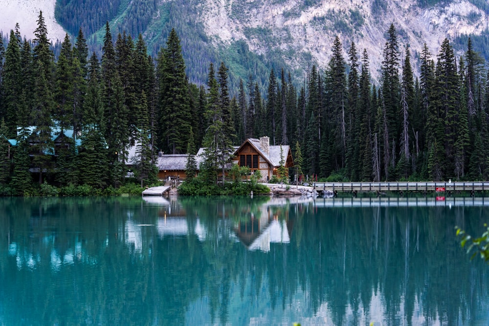 a house on a lake surrounded by trees and mountains