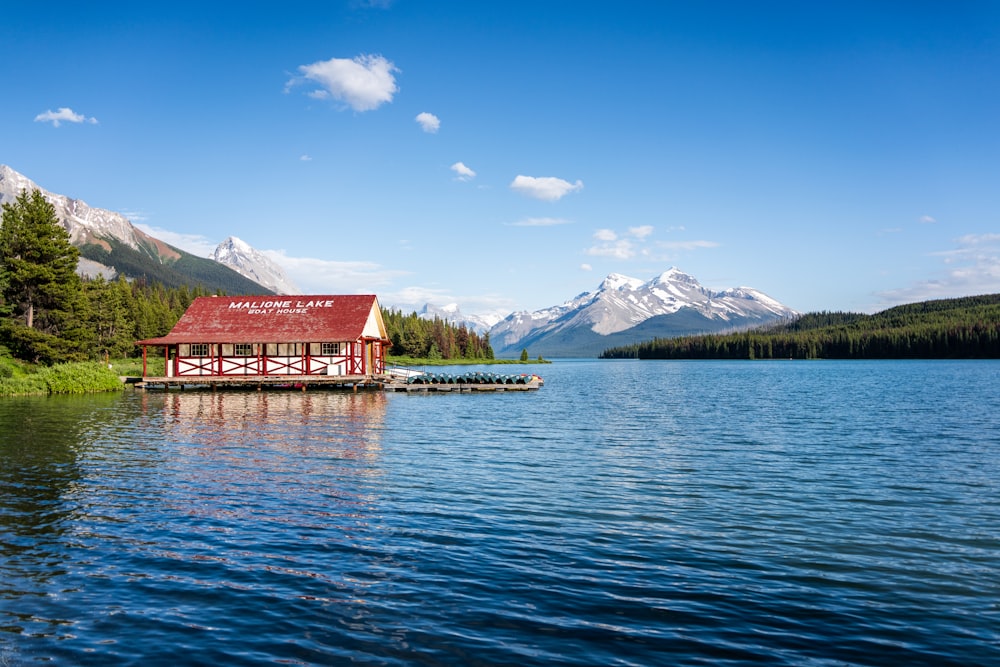 a building on a dock in a lake with mountains in the background