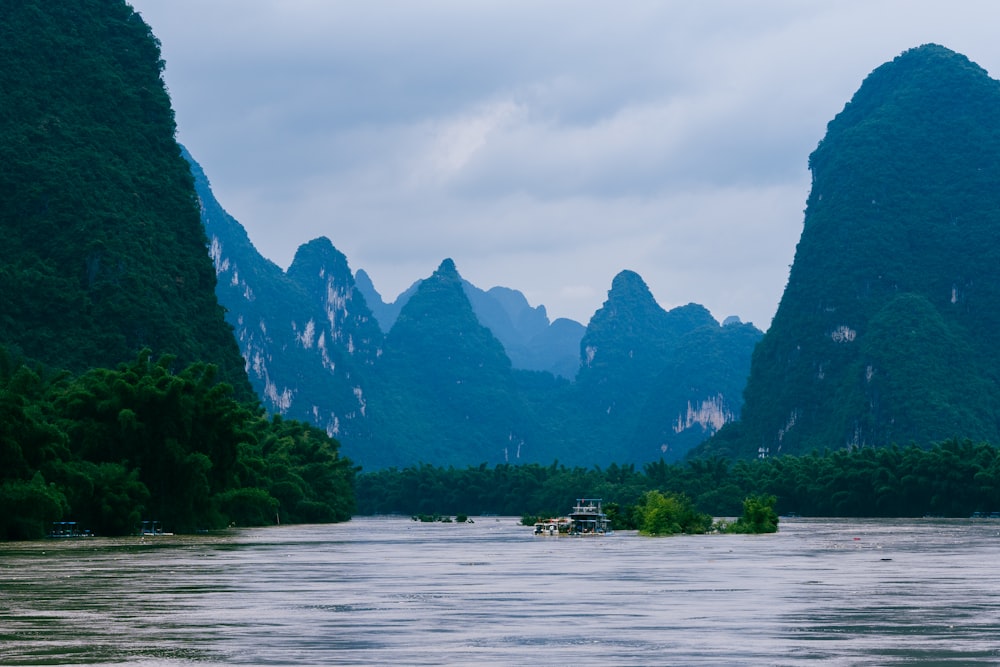 a boat on the water with mountains in the background with Li River in the background