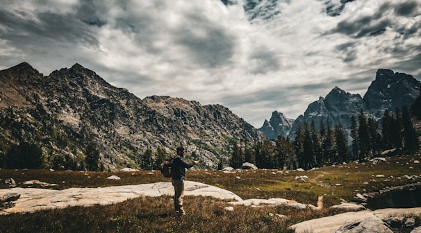 a person standing on a rocky area with mountains in the background