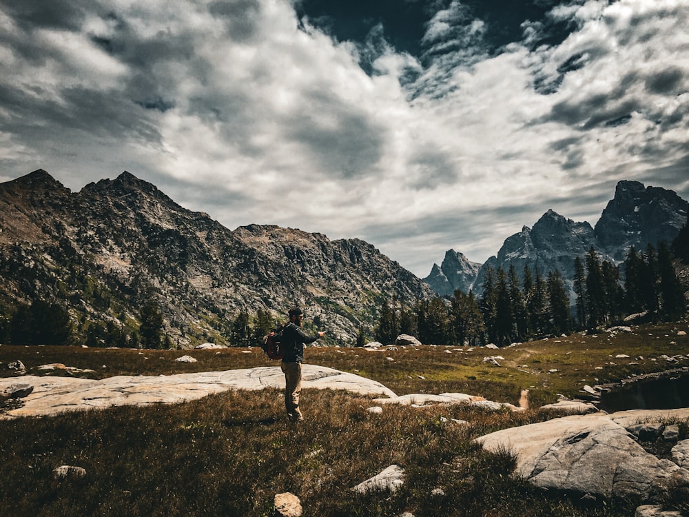 a person standing on a rocky area with mountains in the background