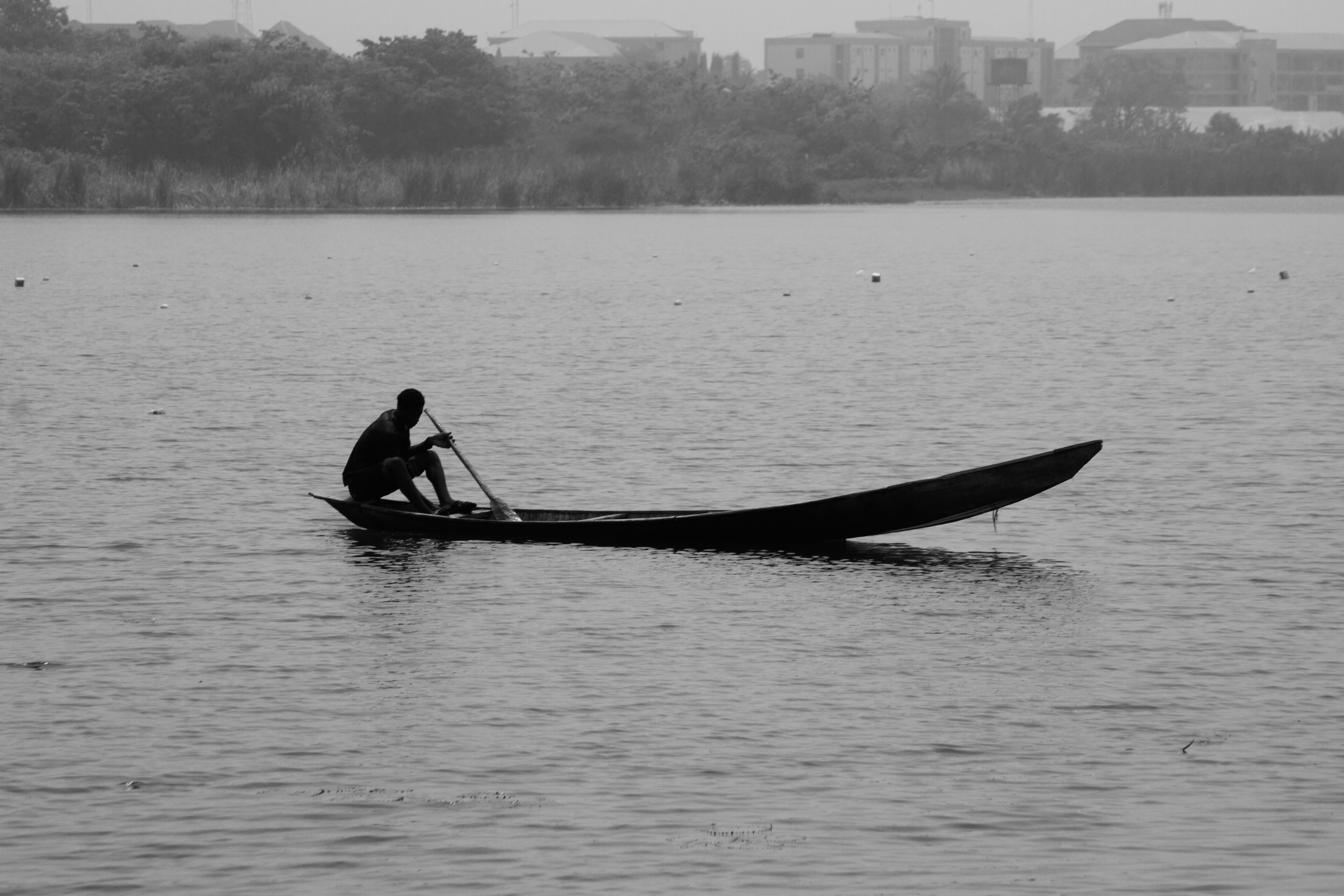 Canoe gliding through misty Algonquin lake at sunrise, dark water, boreal treeline silhouette, perfectly still