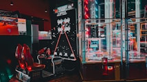 An arcade setting featuring a classic Space Invaders game setup and a modern gaming machine with seats. Bright neon lights illuminate the area, with scores displayed on digital screens. A bright and visually engaging environment full of electronic components.