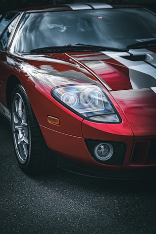 Close-up of a sleek black car with bold red racing stripes glistening under sunlight.