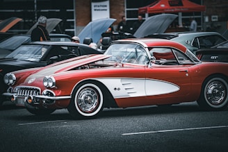 A classic car parked at a vintage event with people admiring it.