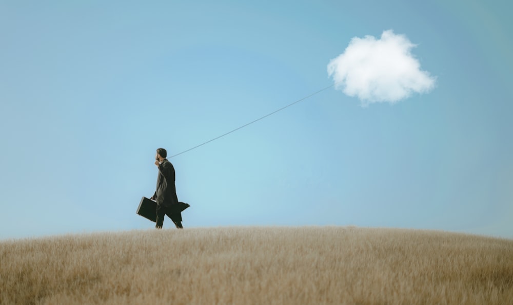 a man in a suit and tie walking in a field with a parachute