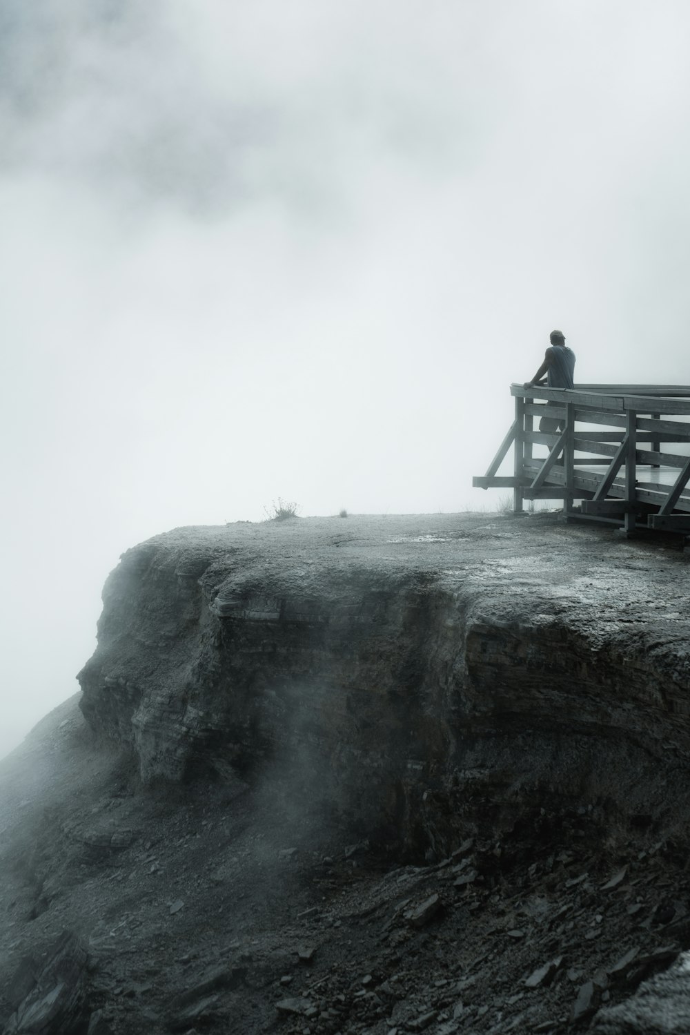 a person sitting on a bench next to a large rock