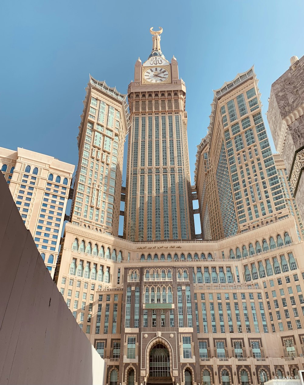 un grande edificio con un orologio su di esso con Abraj Al Bait sullo sfondo