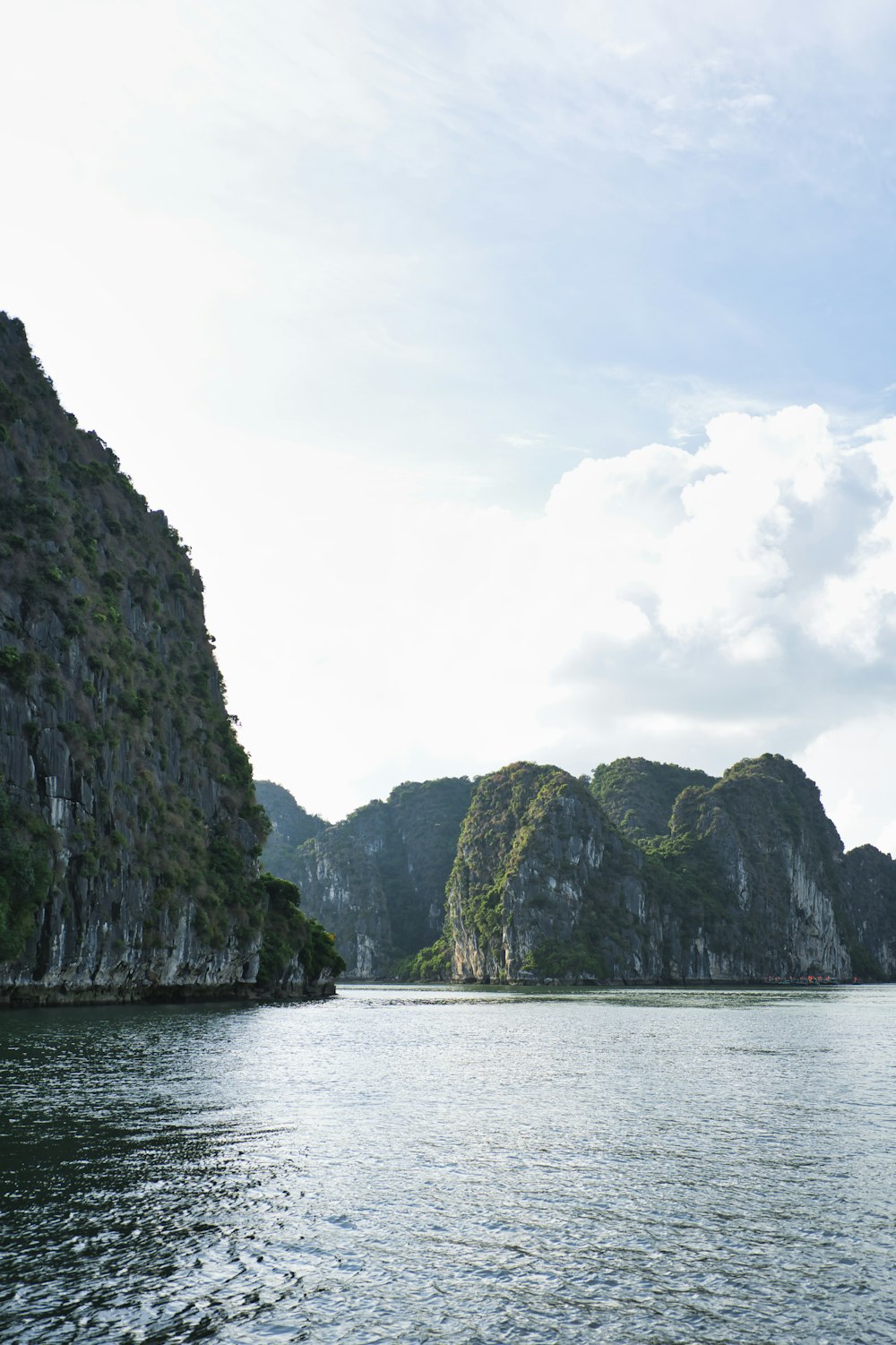 a body of water with cliffs and a cloudy sky