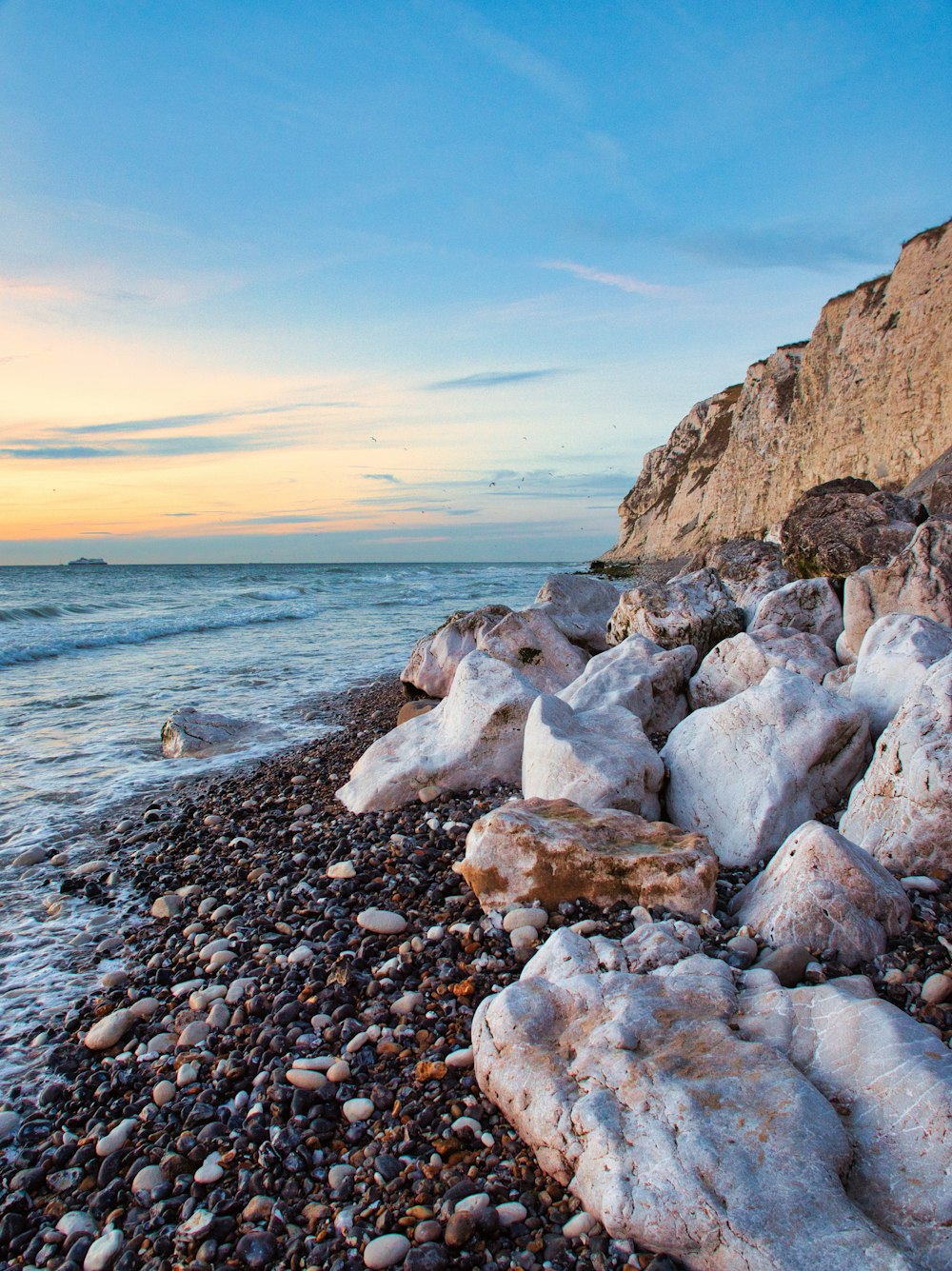 a rocky beach with water and a sunset