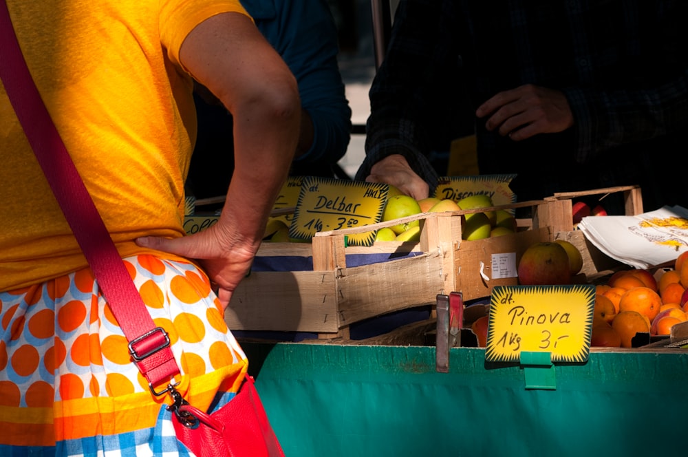 Una persona con un delantal naranja vendiendo frutas
