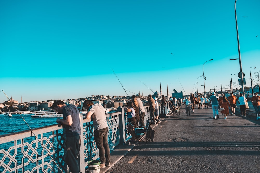 a group of people standing on a bridge over water