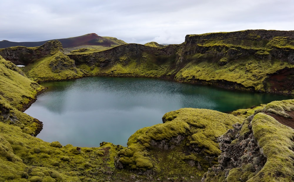 a body of water surrounded by green hills