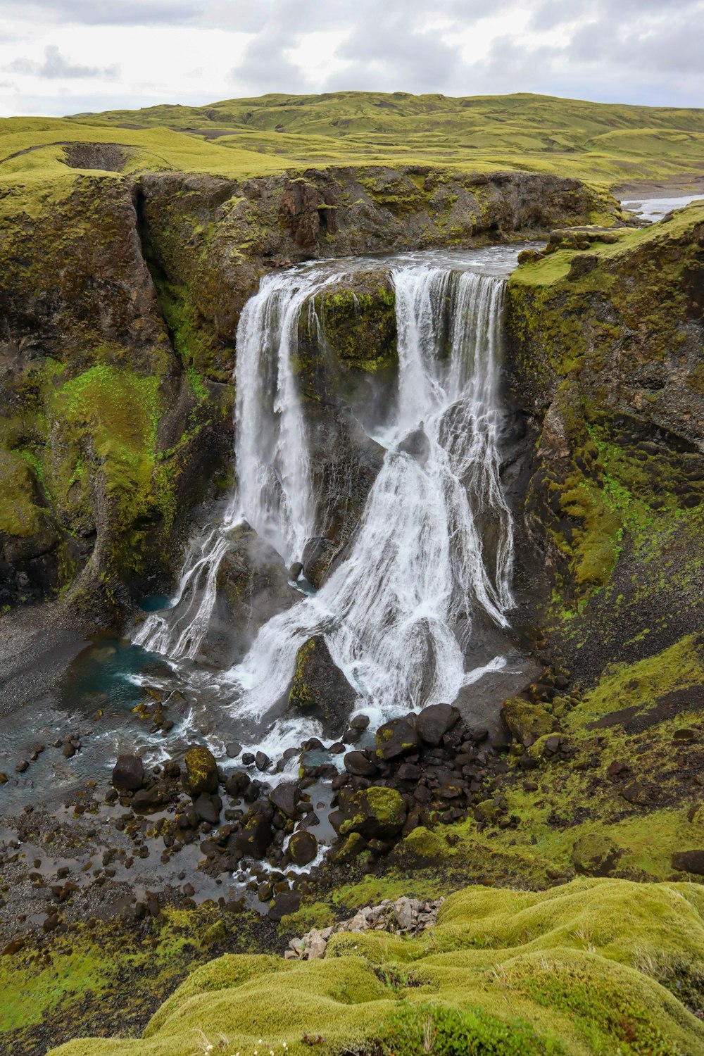 a waterfall in a grassy area