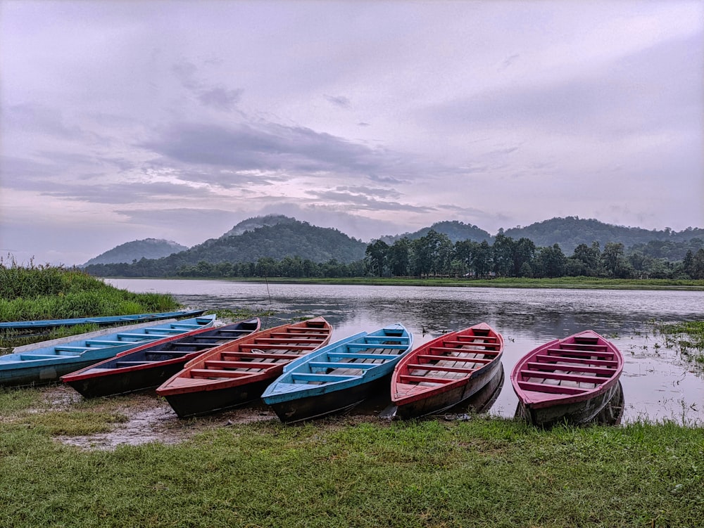 a group of boats sit on the shore of a lake