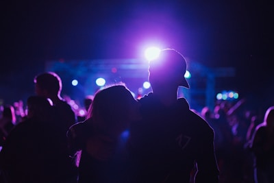 A cheerful pair enjoying a lively concert together under colorful stage lights.