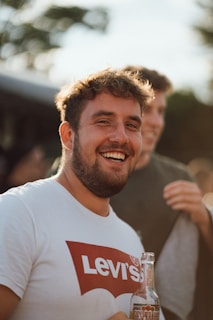 a man smiling with a bottle of beer in front of him