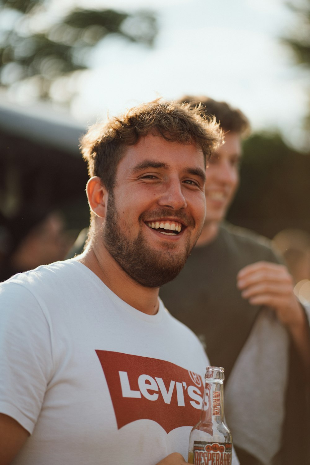 a man smiling with a bottle of beer in front of him