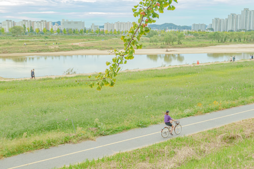 a person riding a bicycle on a road next to a body of water