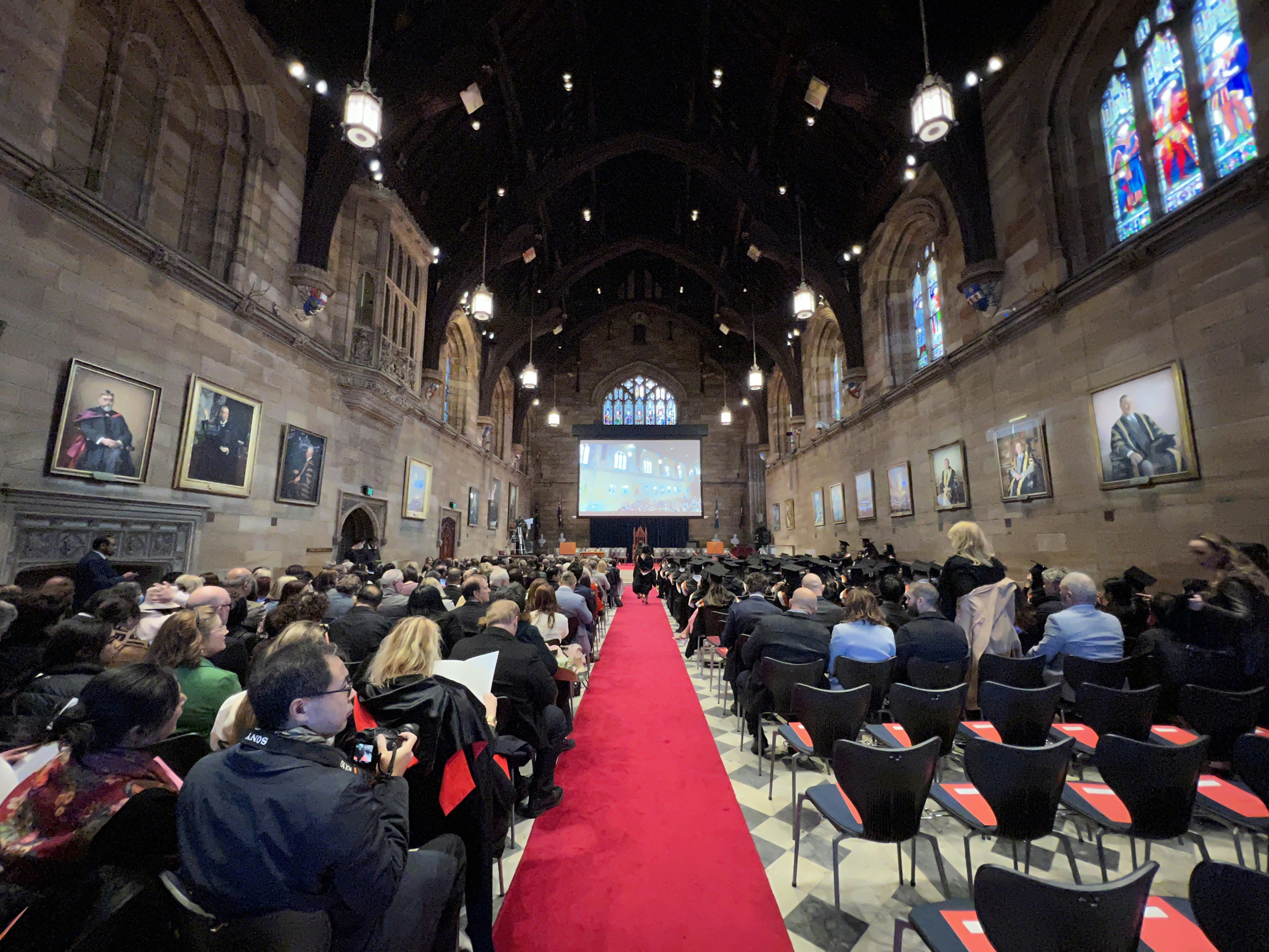 a group of people sitting in a room with a large screen