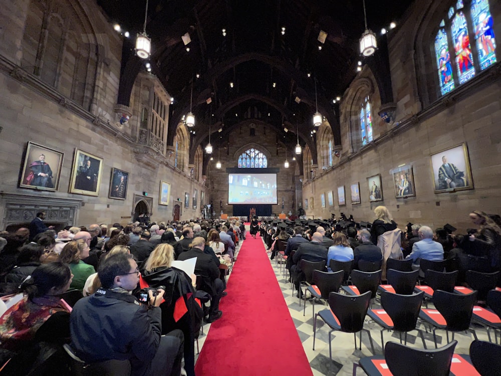 a group of people sitting in a room with a large screen