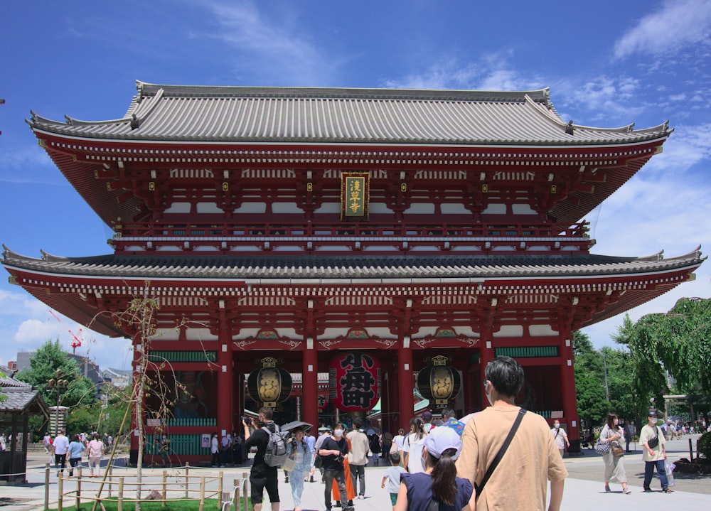 a red asian building with people walking around