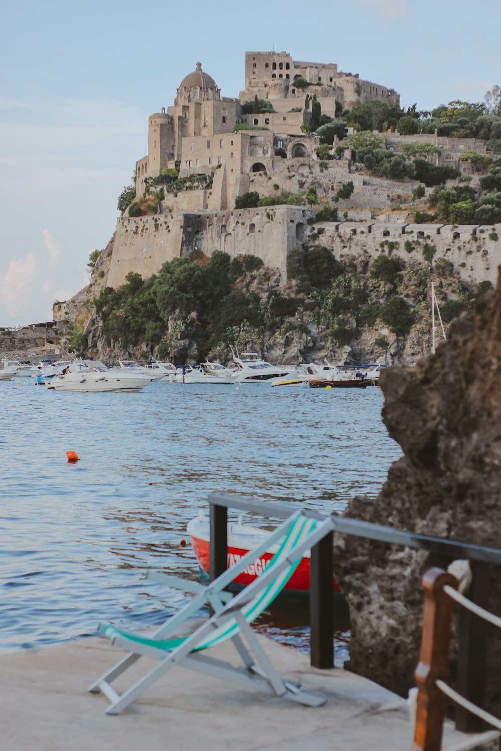 a chair on a balcony overlooking a body of water with boats in it